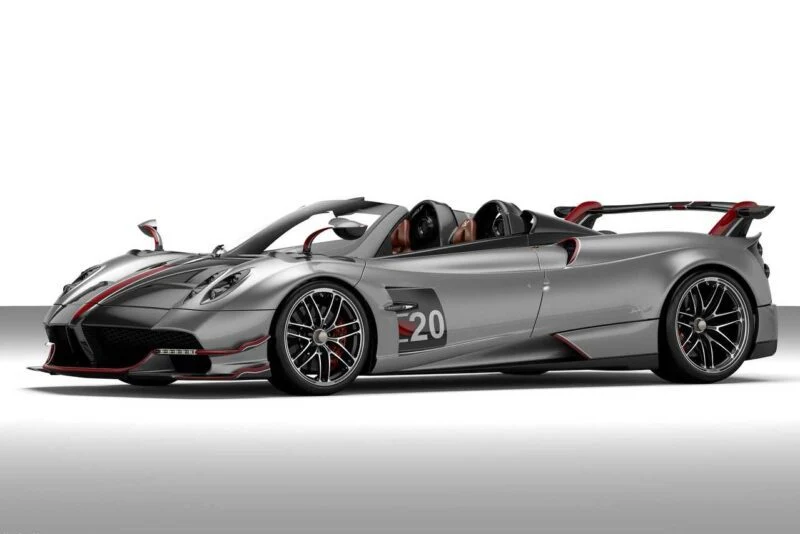 A silver and black convertible sports car with red accents, the number 20 on the door, and a large rear wing, reminiscent of vehicles Pagani will showcase at the upcoming 9th Historic Minardi Day in Imola. Displayed in a studio setting.