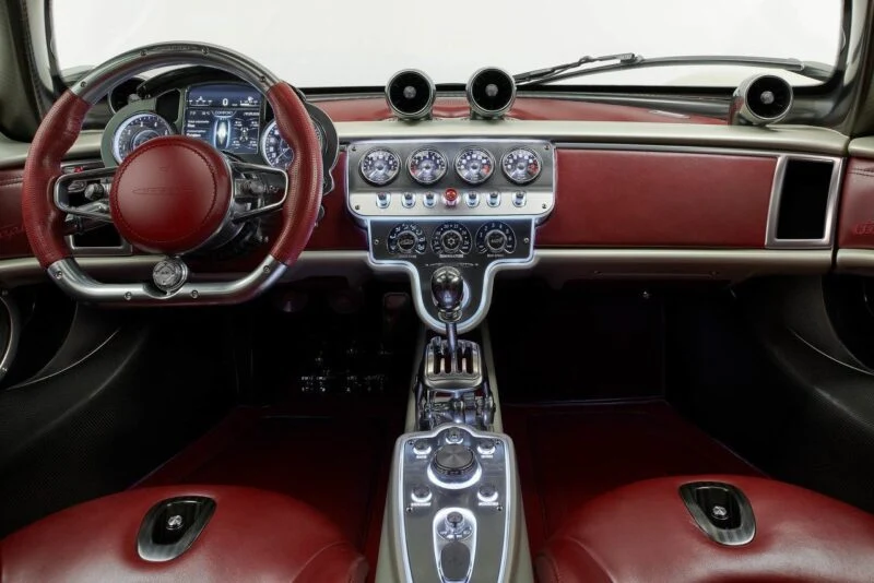 Red and silver luxury car interior featuring a leather-wrapped steering wheel, central gauges, control buttons, and an advanced digital display—reminiscent of Pagani to Showcase Four Hypercar Icons at the Upcoming 9th Historic Minardi Day in Imola.