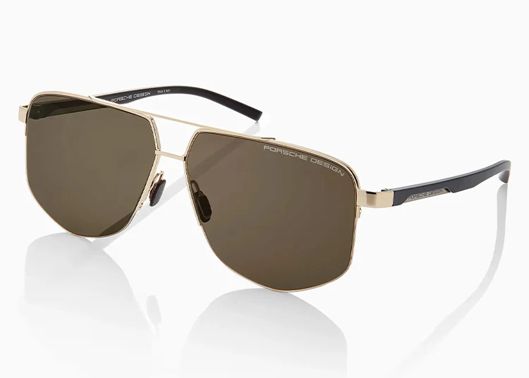 Gold-framed Porsche Design sunglasses with dark tinted lenses and black temple arms, shown on a white background—an ideal pick for the 2025 Holiday Gift Guide.