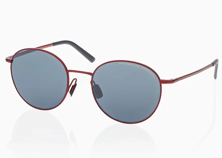 Round sunglasses with a thin red metal frame, gray lenses, black temple tips, and the