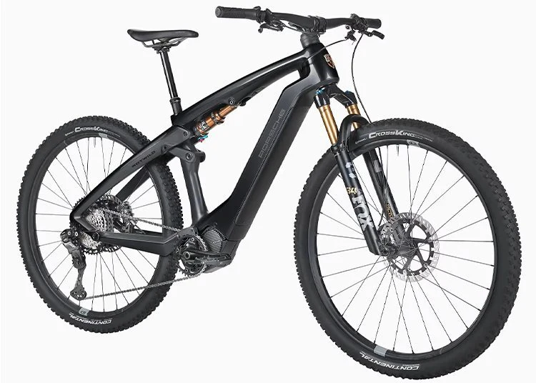 Matte black 2025 Porsche Design electric mountain bike with front and rear suspension, disc brakes, wide tires, and a sturdy frame, viewed at a slight angle from the front left side—an ideal pick for any Holiday Gift Guide.