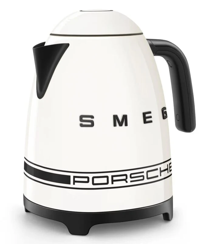 A white electric kettle with black accents displays the SMEG logo and Porsche Design branding on the side—an elegant pick for any 2025 Holiday Gift Guide.