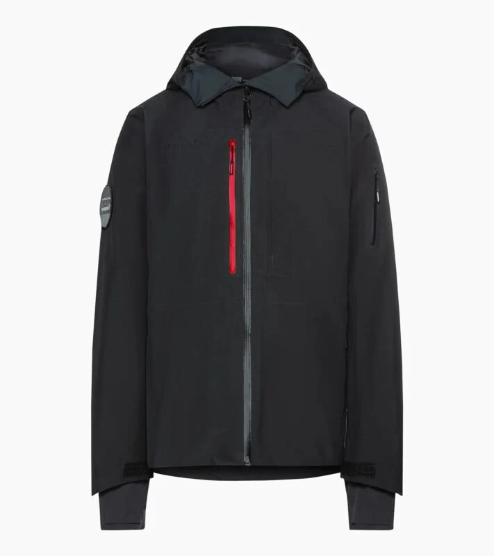 A black Porsche Design hooded jacket with a front zipper, a red vertical chest pocket, and an arm pocket on the left sleeve, displayed on a white background—an ideal pick for your 2025 Holiday Gift Guide.