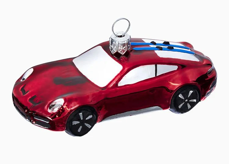 A red car-shaped Christmas ornament with white windows, black wheels, and a blue-striped detail on the roof—perfect for any Porsche Design enthusiast or as a unique pick in your 2025 Holiday Gift Guide.