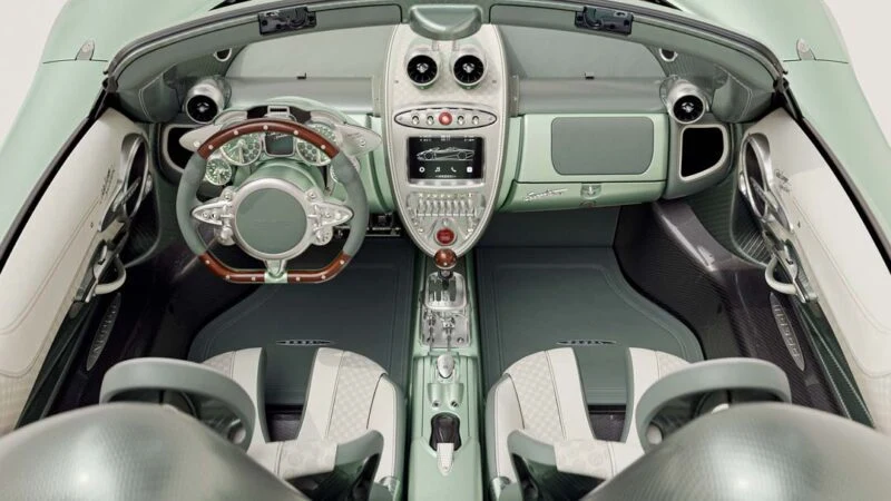 Luxury car interior featuring green leather seats, a wooden-trimmed steering wheel, and a central control panel with metallic accents—exemplifying the craftsmanship of the limited edition Pagani Huayra Codalunga by Pagani Automobili.