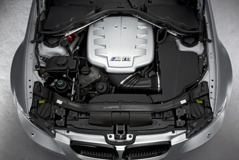 View of a BMW E90 M3 engine bay with a silver M V8 engine cover, showcasing various components from above—a true collector car worth over $250K to the right enthusiast.