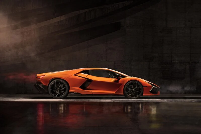 A Lamborghini Revuelto sports car gleams in the dimly lit space, its sleek design captured in the polished reflection on the floor, hinting at its impressive specs without a word on price.