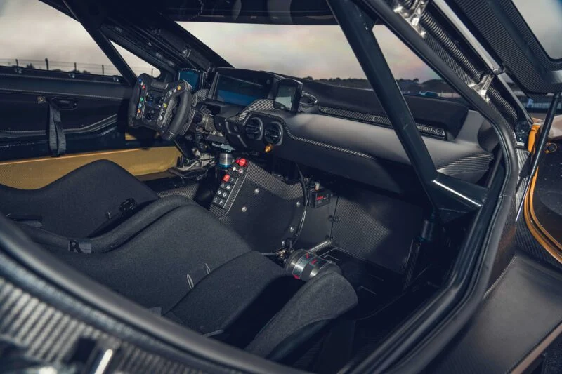 Interior view of a race car cockpit—similar to the Ford Performance Launches Final Production Run of Legendary Ford GT Mk IV—featuring bucket seats, a digital dashboard, racing steering wheel, control switches, and a roll cage.