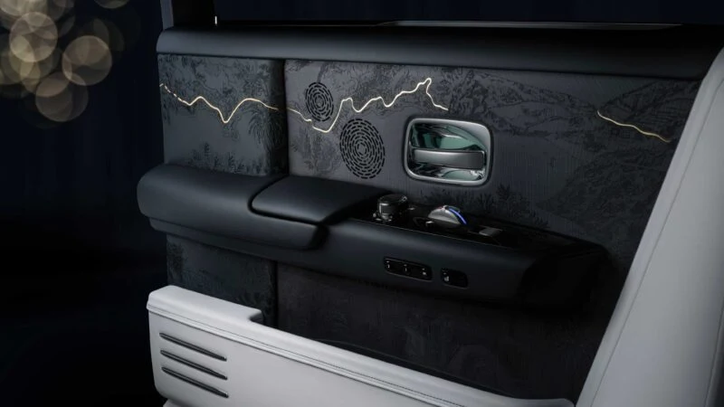 Close-up of a luxury car door interior featuring embroidered detailing, ambient lighting, and sleek control buttons—part of the Rolls-Royce Honors 100 Years Of Phantom With Groundbreaking Private Collection.